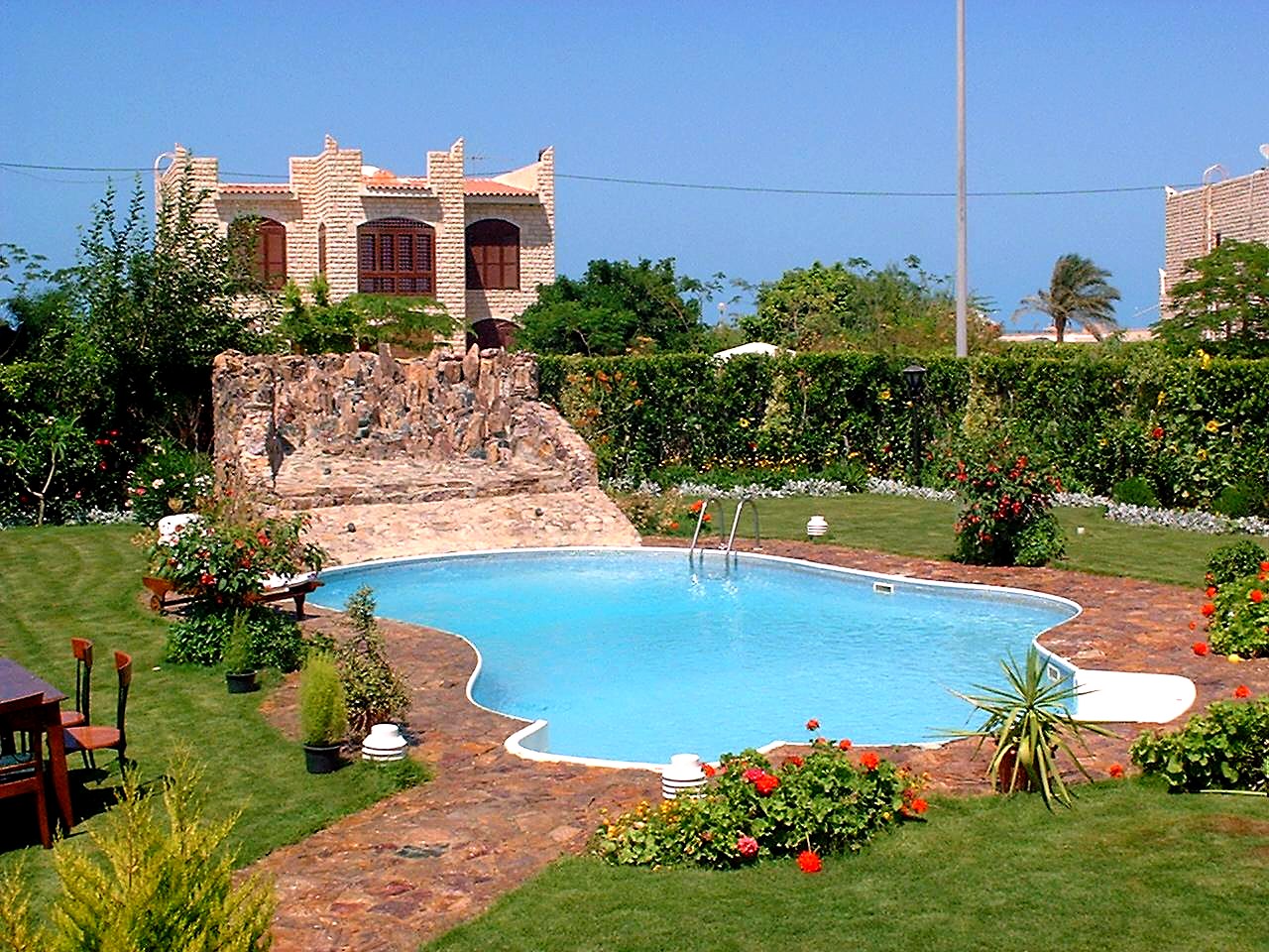 Villa pool with rock waterfall and flowering garden